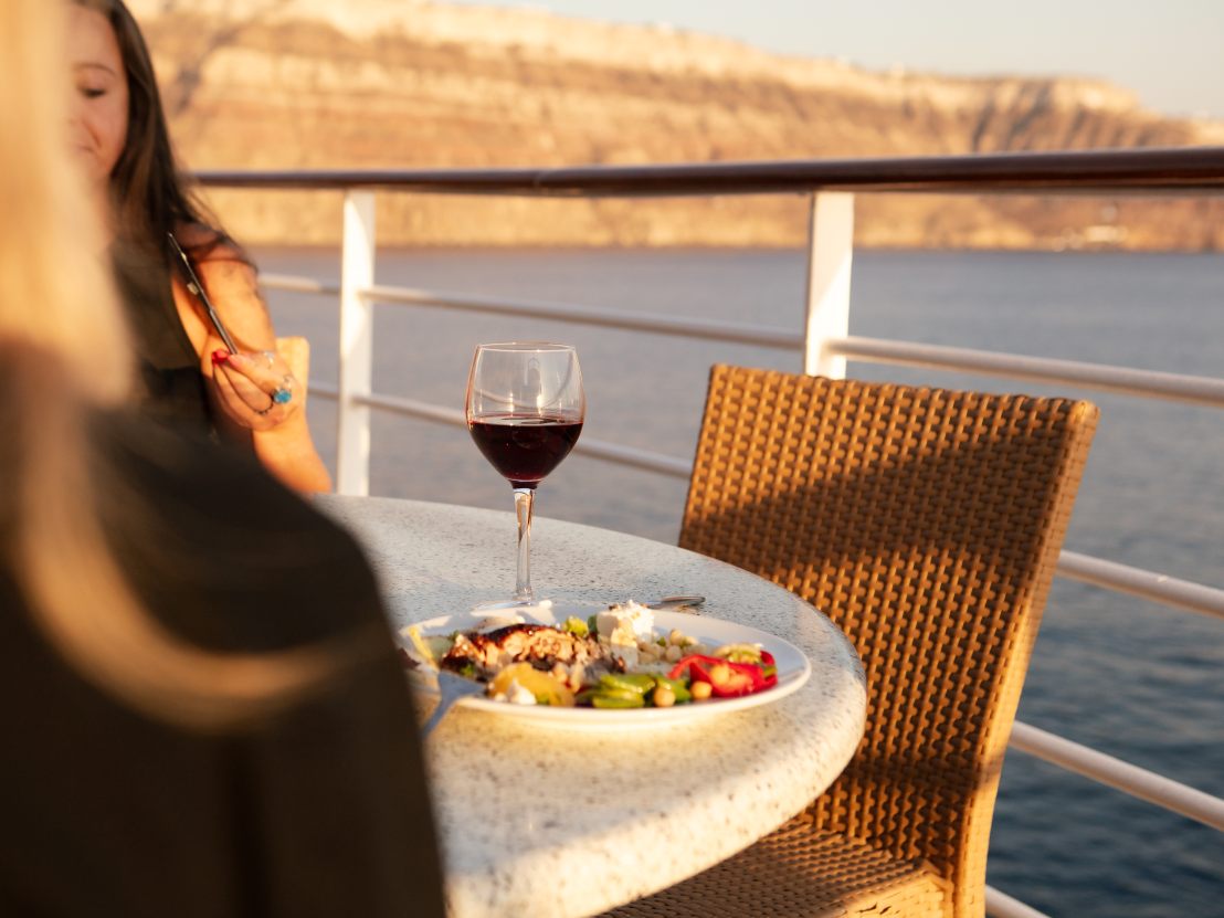 Alfresco dining on deck, with Santorini astern